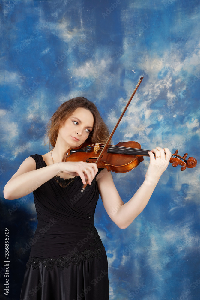 Young woman playing the violin against abstract blue background.