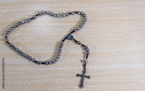 Rosary and crucifix symbols of Catholicism on light wooden background