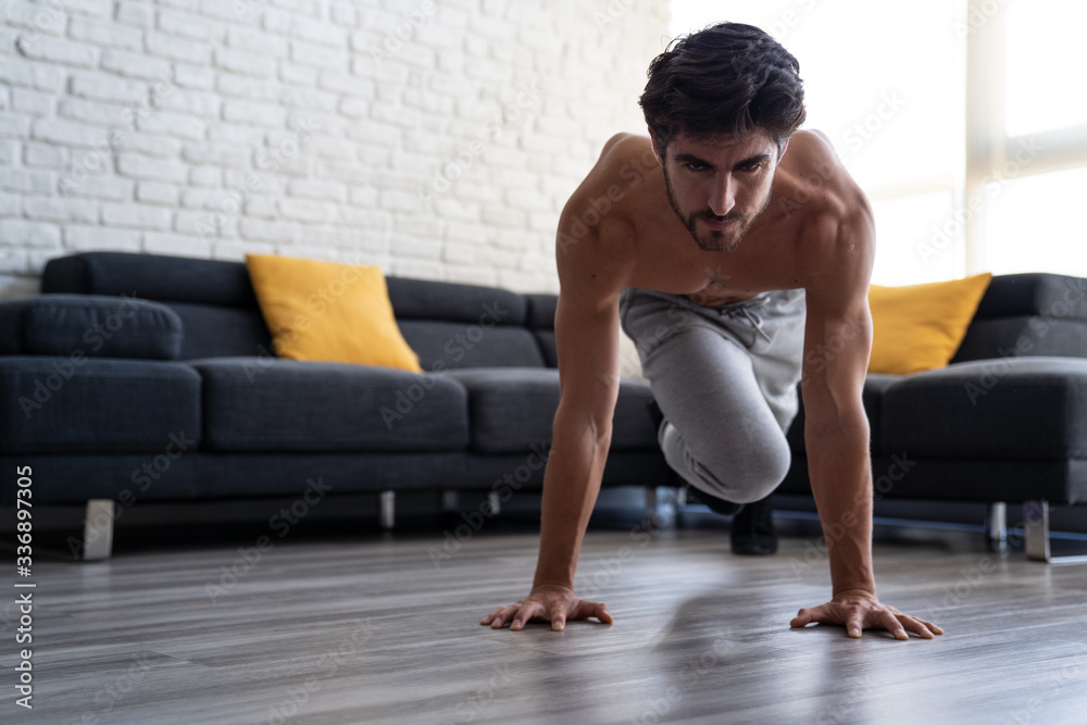 Obraz premium Portait Athletic White Young Man Doing Abs Workout Home Alone