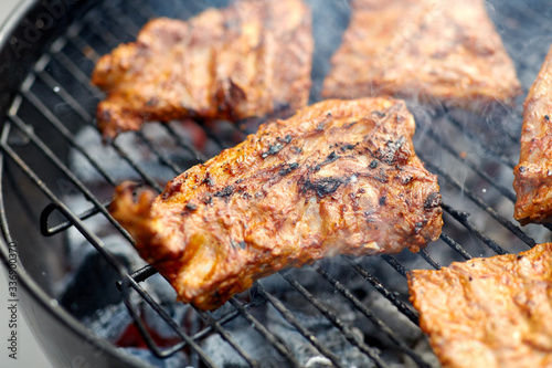 cooking, culinary and food concept - close up of barbecue meat roasting on brazier grill outdoors