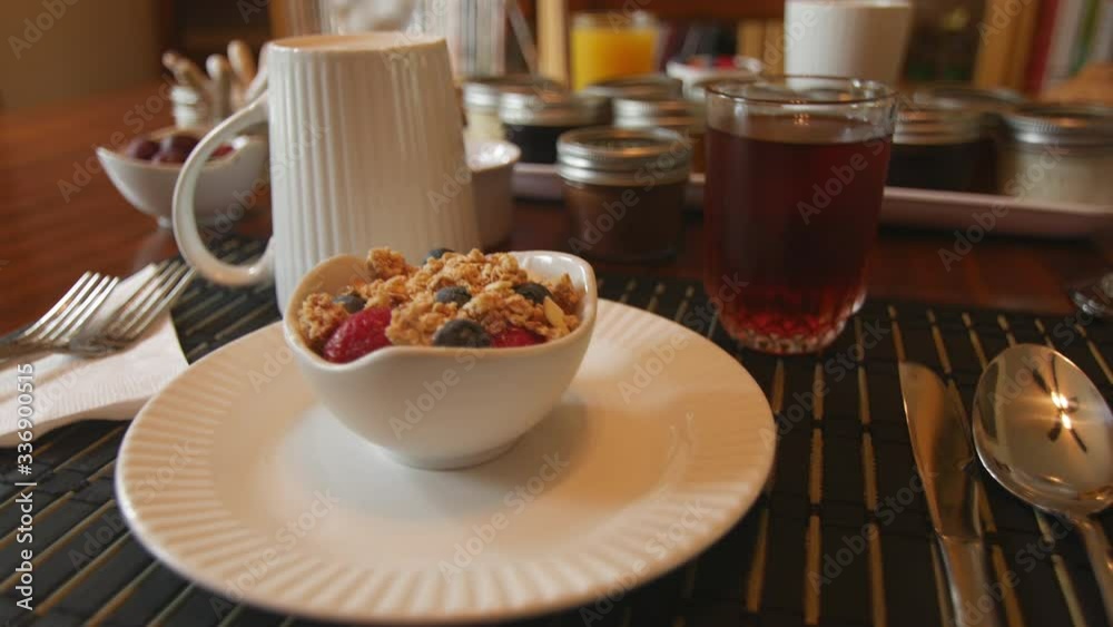 Tracking shot of a delicious bowl of granola with strawberries and blueberries on a neat breakfast table Tracking shot of a delicious bowl of granola with strawberries and blueberries on a neat breakfast table