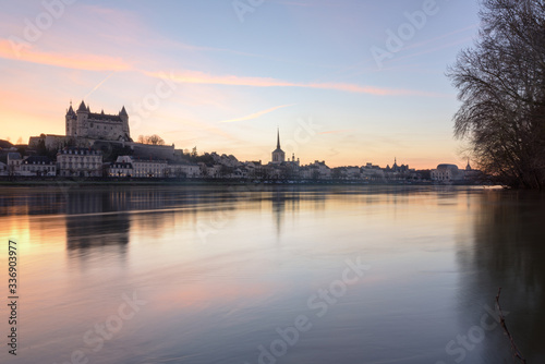 Panorama view of Saumur town from across the Loire river at sunset  with the medieval castle and the old town with Saint-Pierre church