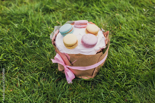 Easter cake decorated with icing and macaroons on green grass. Traditional holiday baking