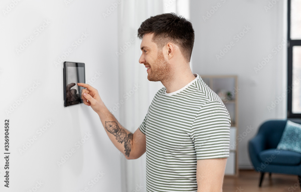 automation, internet of things and technology concept - happy smiling man using tablet pc computer at smart home automation, internet of things and technology concept - happy smiling man using tablet pc computer at smart home