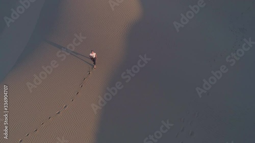 4k aerial video of a beautiful Girl taking photos on sand dunes at sunset