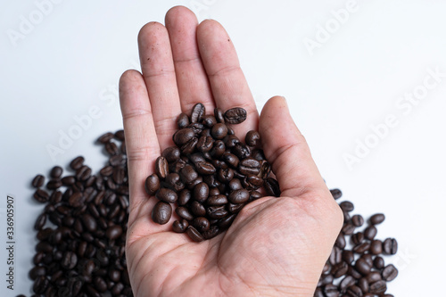 roasted coffee beans and hand in selective focus.