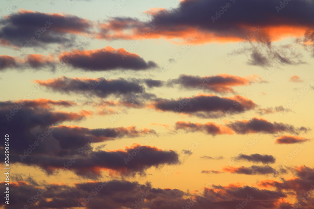 Fototapeta premium Clouds in the blue sky at sunset or dawn backlit by the sun. Place for text and design.
