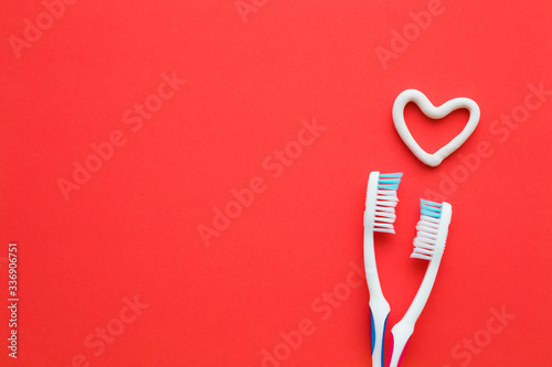 Fotografi Two white toothbrushes on bright red background