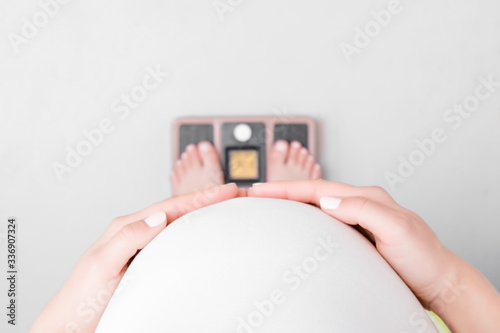 Quadro em tela Young pregnant woman with barefoot standing on weight scales