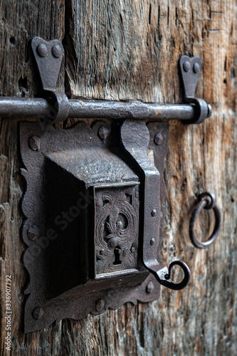Ancient rusty steel lock bolt with a key hole installed on an old wooden door from medieval age