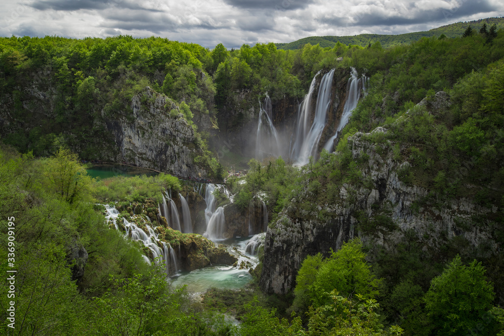 Panoramic view of the biggest waterfall called veliki slap in plitvice lakes, croatia on a cloudy spring day. Big waterfall surrounded by lush greens in springtime.