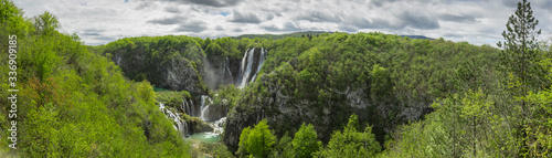 Panoramic view of the biggest waterfall called veliki slap in plitvice lakes  croatia on a cloudy spring day. Big waterfall surrounded by lush greens in springtime.