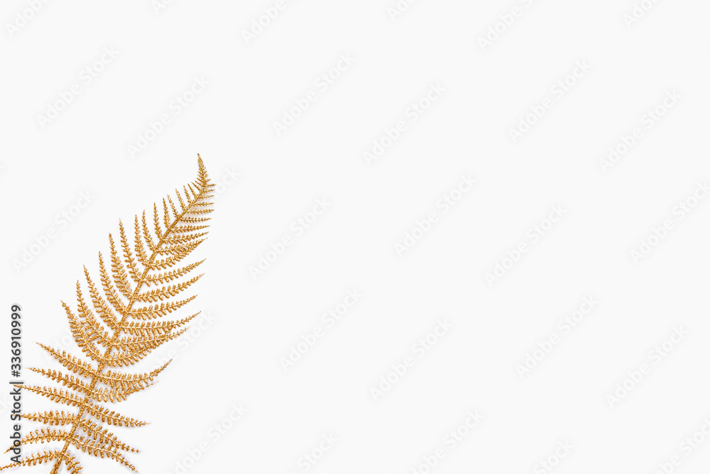 Golden fern leaf over white background. Copy space.