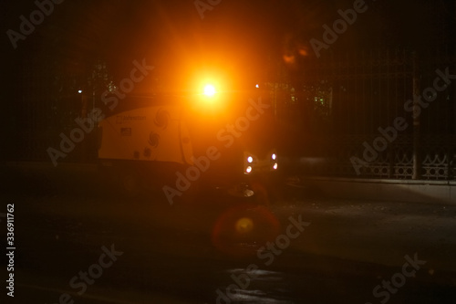 A small size sweeper cleans the street at night with a yellow flashing light on the roof | EKATERINBURG, RUSSIA - 8 APRIL 2020.