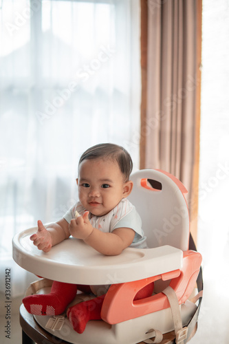 happy asian baby feeding time sitting on highchair