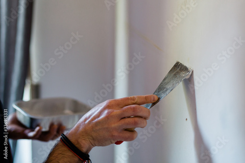 Doing homework. Adult man repairing holes on a wall with putty