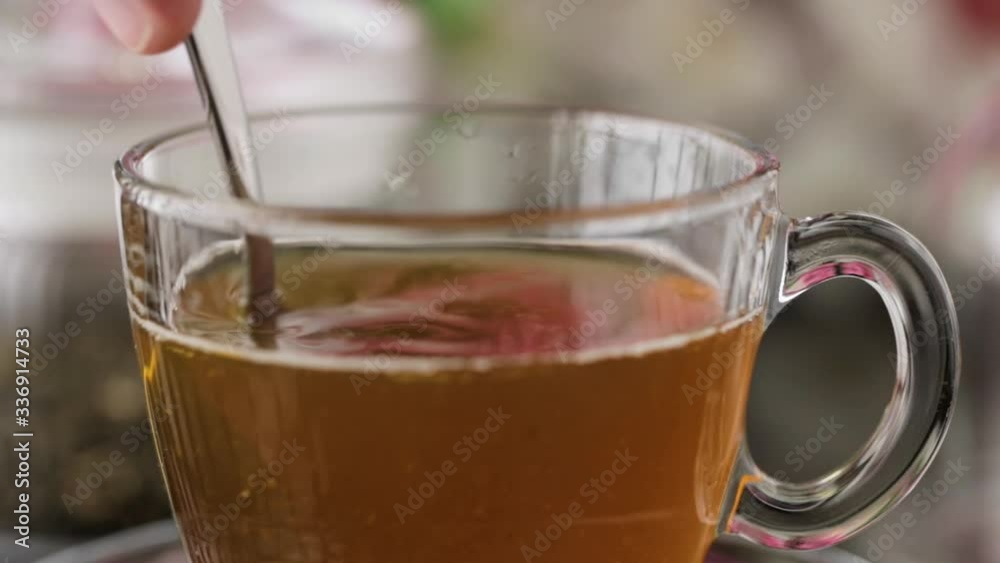 Tea pouring closeup. Tea being poured into glass transparent tea cup. Tea time concept. Transparent glass teapot and teacup. Herbal tea, green tea, tea with Jasmine. Put the sugar in a Cup and stir.