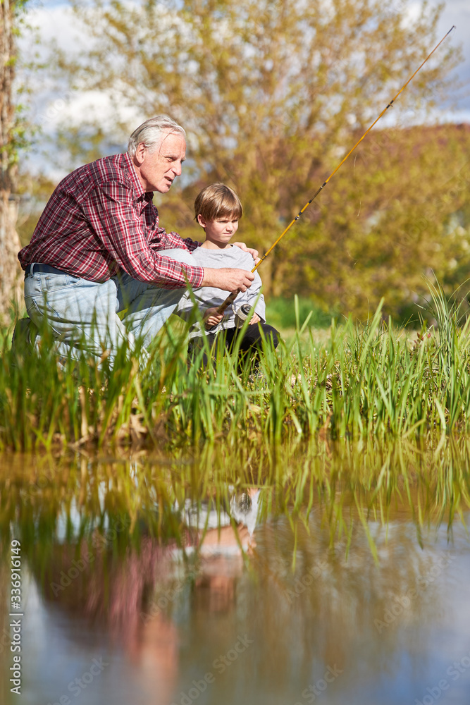 Fototapeta premium Grandpa shows and explains fishing to his grandson