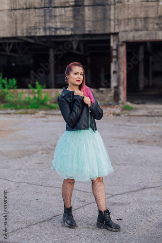 Portrait of a young girl with pink hair standing outside of collapsed building