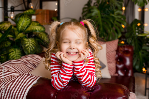 Little blonde girl sits on the couch at home and laughs. stay at home © КРИСТИНА Игумнова