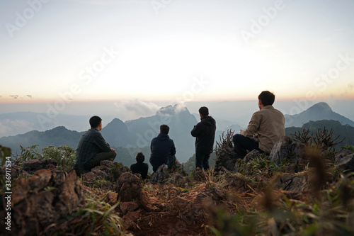 A group of hiker on the peak looking at green mountain range with cloudy sky © chettarin