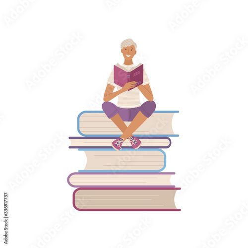 Young man reading book on stack of big books