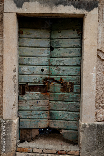 Green wooden door locked with a chain and a padlock golden iron