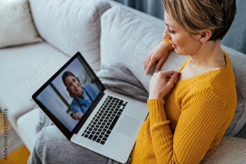 Obraz na plátne Woman using laptop and having video call with her doctor while sitting at home