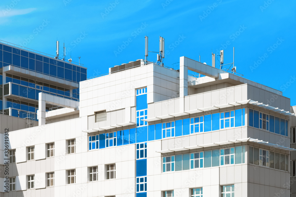 Modern hospital building with blue cross shaped windows against blue sky