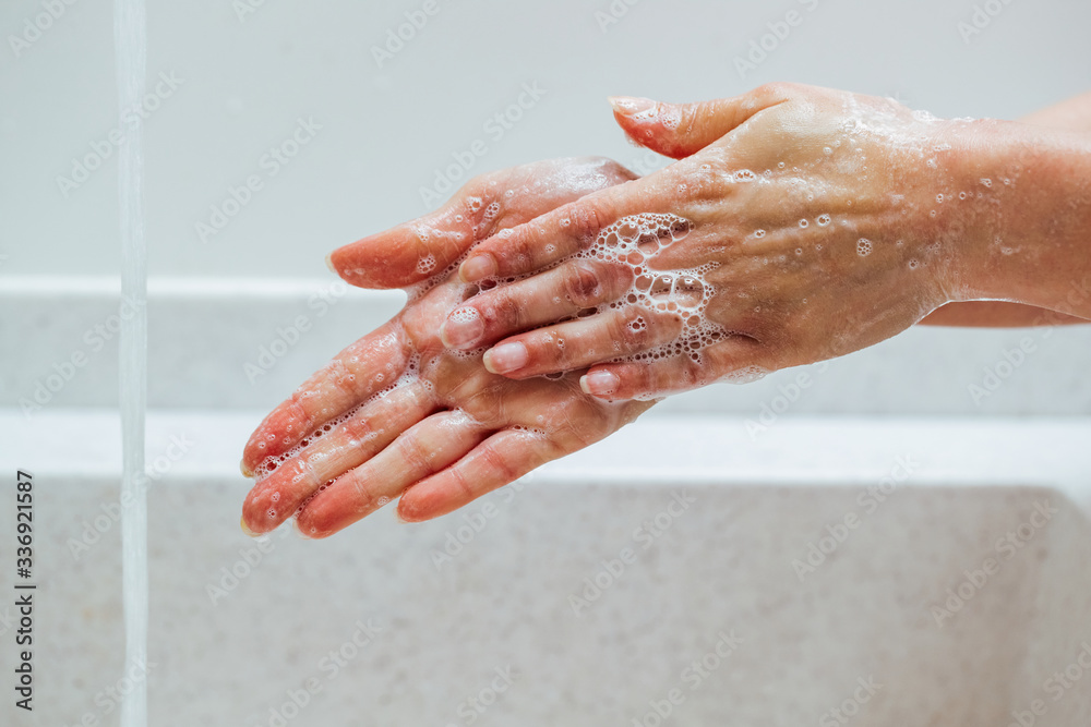 Close-up of woman rubbing hands with a soap under bathroom sink. Close-up of woman rubbing hands with a soap under bathroom sink.