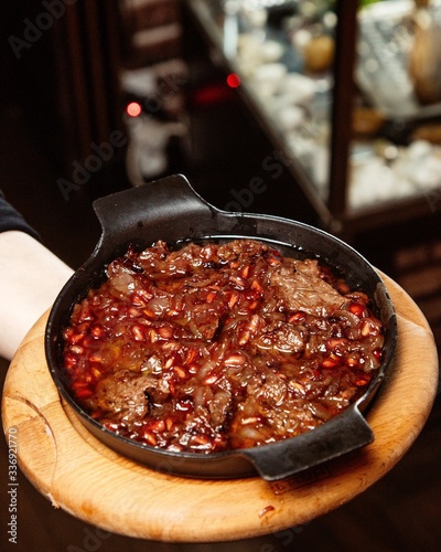 lamb stew with onion and pomegranate seed in cast iron pan photo