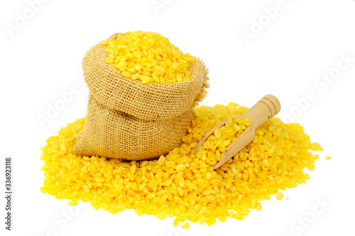 Organic split yellow mung beans (Yellow Moong Dal, Moong split washed, Lentisls) in a sack surrounded by organic split yellow mung beans with wooden spoon.