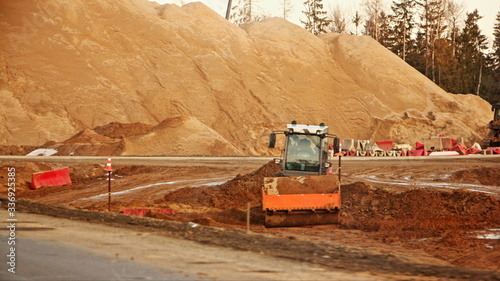 A skating rink levels the ground on a construction site against the background of a mountain of sand