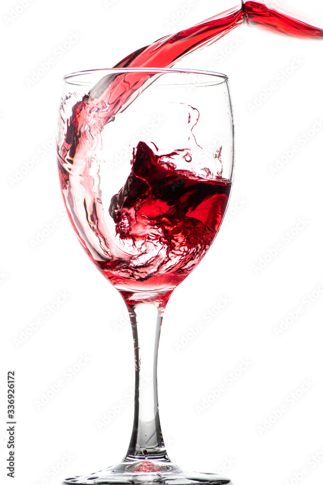 Splash of falling red wine in a round glass on a white background Splash of falling red wine in a round glass on a white background