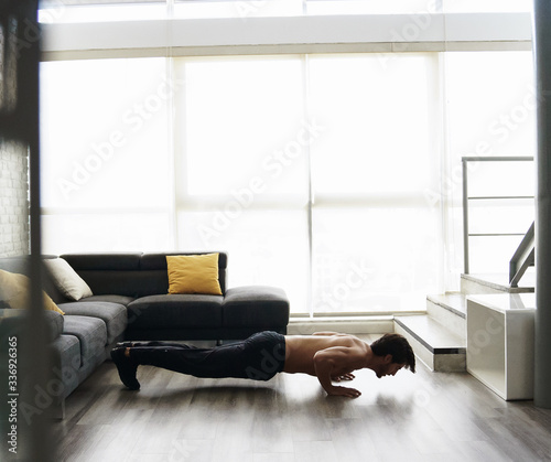 Young adult male working out at home doing push ups.