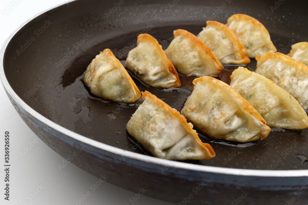 Frozen dumplings fried in oil on a frying pan Frozen dumplings fried in oil on a frying pan
