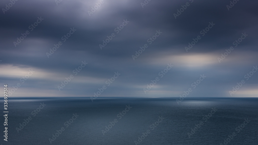 Looking out to the ocean horizon from St Alban's Head as the sun tried to break through the dark clouds, Dorset, UK