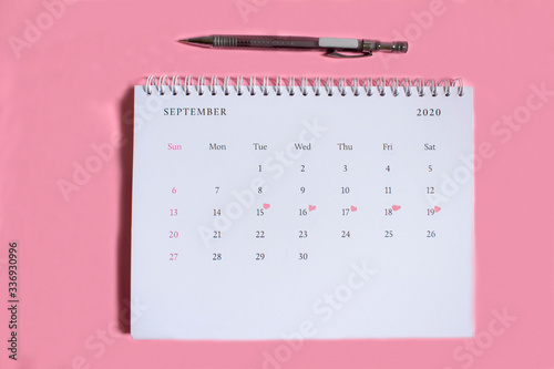 Marked calendar with marker on pink background.