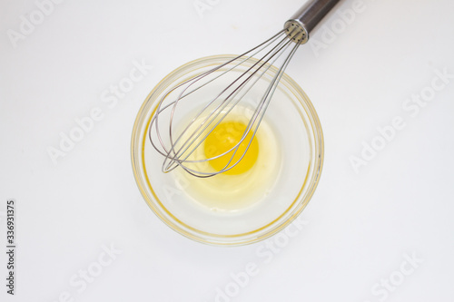 metal whisk and chicken yolk in a glass bowl