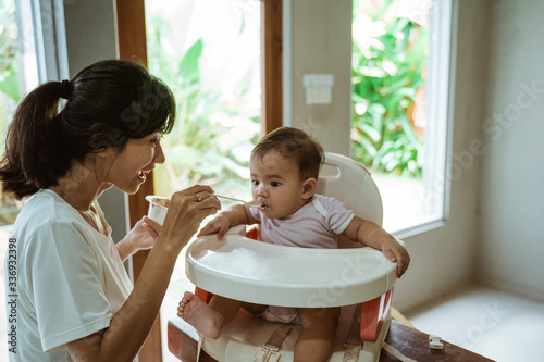 mother feeding baby. asian woman feed her baby at home