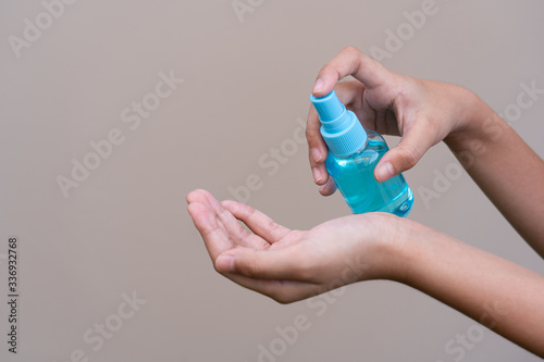 Asian girl kid using blue hand sanitizer spray in clear pump bottle , that use for killing germs, bacteria and viruses. Prevent the spread of germs and bacteria and avoid infections corona virus.