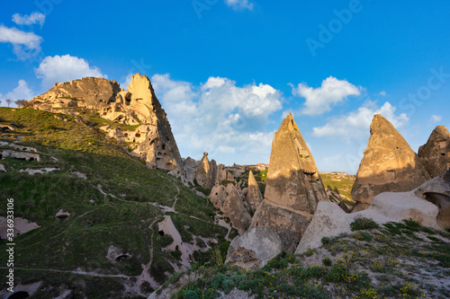 Uchisar Castle and the town are sandstone mountains filled with tunnels and windows. In the morning, the sun hits the golden peaks and blue skies of Cappadocia, Turkey.