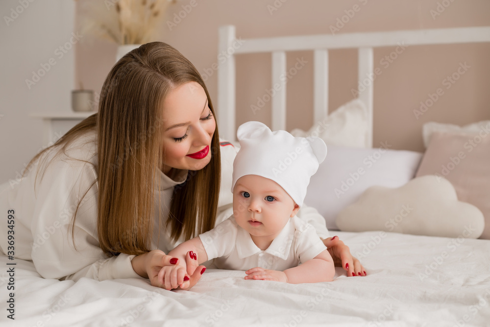 Happy young mother hugs toddler at home on bed Happy young mother hugs toddler at home on bed