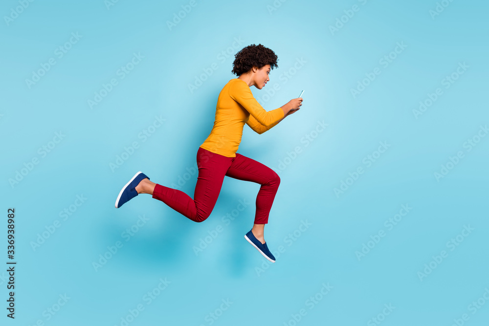 Fototapeta premium Full length body size view of her she nice attractive lovely addicted focused wavy-haired girl jumping running fast hurry rush using cell isolated on bright vivid shine vibrant blue color background