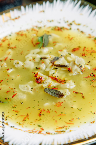 Azerbaijani restaurant dish with vegetable decor on a wooden background. Yellow soup dushbara in the plate of dumplings. photo