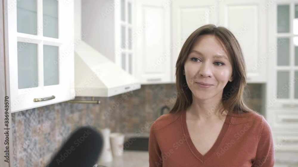 Happy young woman during interview with journalist. Reporter with microphone interviews girl at home kitchen. Blogger films vlog for internet channel. Happy young woman during interview with journalist. Reporter with microphone interviews girl at home kitchen. Blogger films vlog for internet channel.