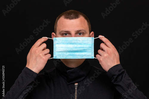 a man puts on a medical mask on his face, instructions on how to wear a mask photo