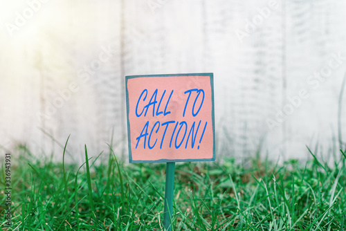 Text sign showing Call To Action. Business photo text exhortation do something in order achieve aim with problem Plain empty paper attached to a stick and placed in the green grassy land photo