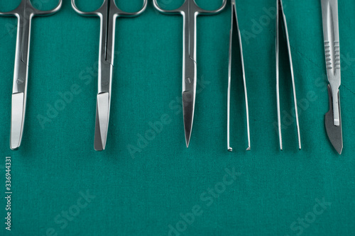 Basic surgical instrument scalpel forceps tweezers scissors on surgical green drape fabric in operation room