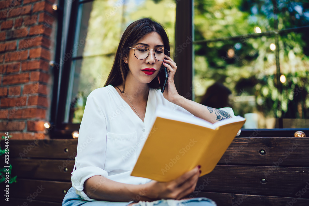 Spanish female student in optical eyewear reading education information